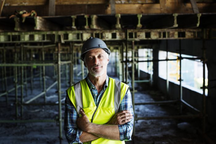 Confident man with arms crossed at a construction site.