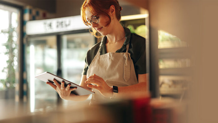 Female business owner uses an iPad to check online reviews of her small business.