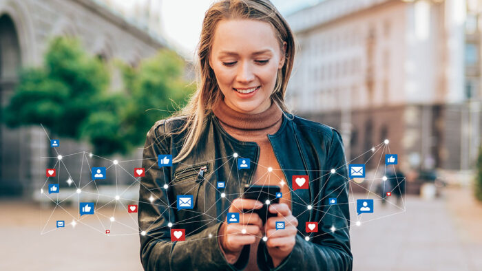 Woman smiles while using her smart phone to engage with businesses on social media.