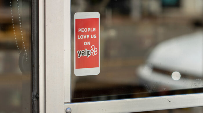 Yelp review sticker on a glass window of a small business storefront.