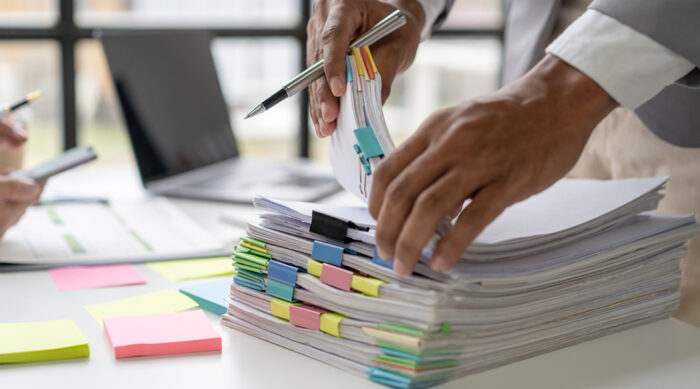 Stacks of paper evidence separated with pastel clips to support an online defamation case.