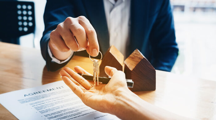 A male property manager hands a new tenant keys to their new apartment.