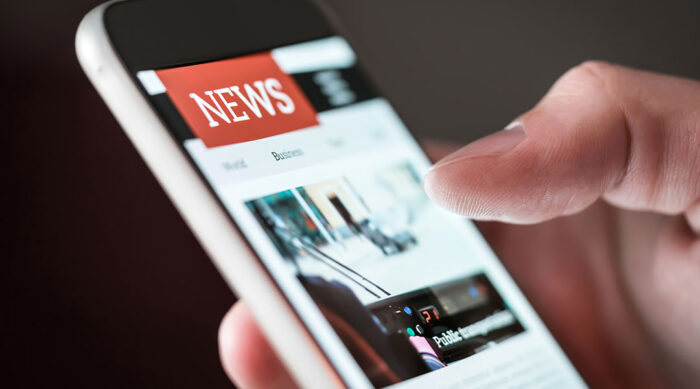 Man reads a news article on a white smartphone.