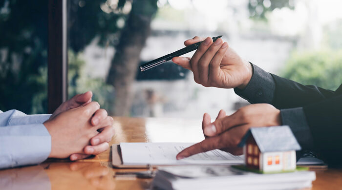 A property manager sits with prospective tenants to review lease documents.