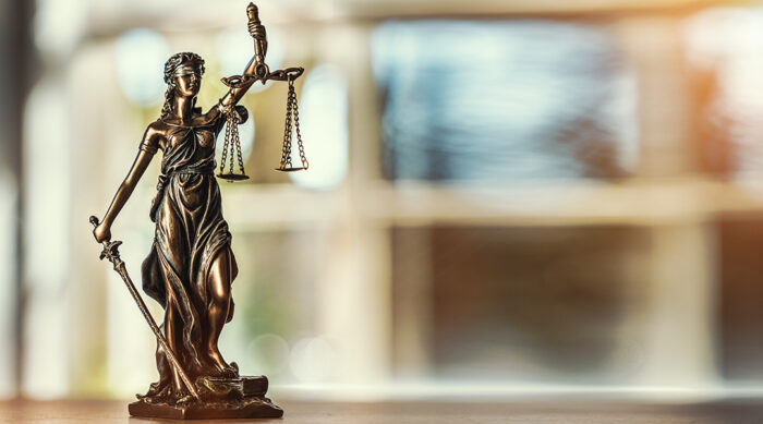 Lady Justice statue on a wooden desk in a lawn firm office.