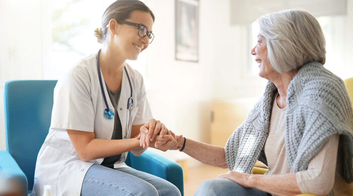 Female doctor holds the hand of an elderly female patient.