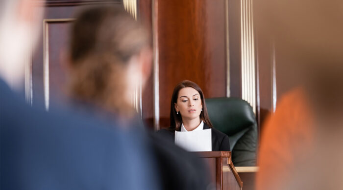 A female judge reviews a defamation lawsuit document in court.