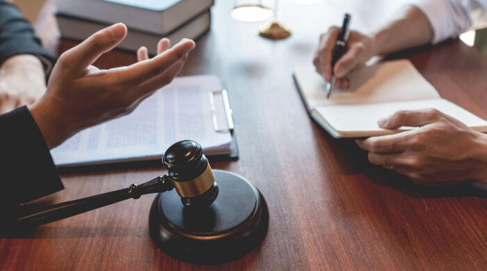Two defamation attorneys sit at a wooden desk and discuss how to win a defamation lawsuit.