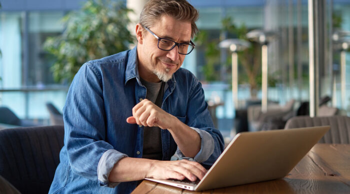 Middle aged man wearing a blue shirt and glasses researches the history of Section 230.