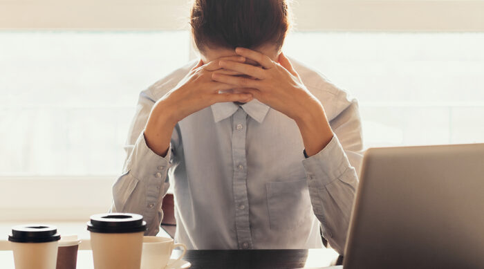 A young woman with her hair tied in a bun holds her hands to her face in a stressful moment.