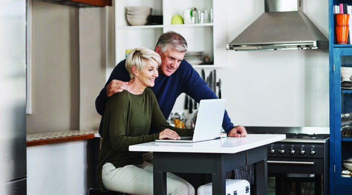 Couple looking over their estate plan on their laptop in their kitchen.