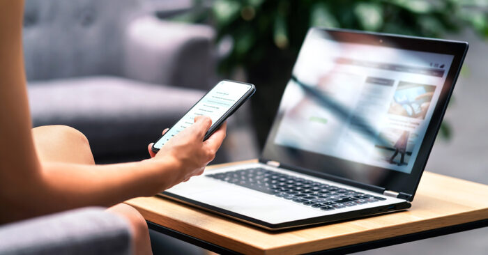 Woman researching Anti-SLAPP statutes on her phone and laptop at home
