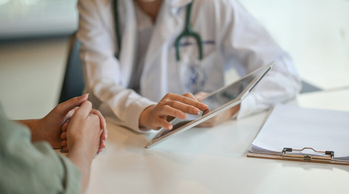 Doctor using tablet to discuss care with patient, illustrating AI in healthcare applications.